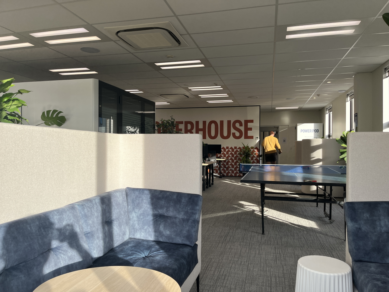 Lounge booth seating and ping pong table at Powerhouse Coworking, with the Powerhouse wall mural in the background